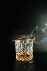 Rocks Glass of whiskey with a smoking cigar
