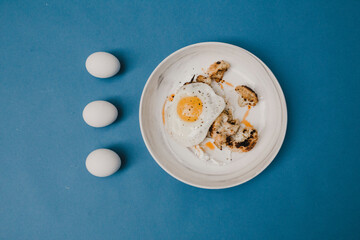 mushrooms and friend egg on plate on blue