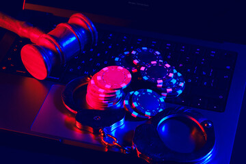 Gavel, Handcuffs, and Poker Chips on a Laptop Keyboard in a Dark Room