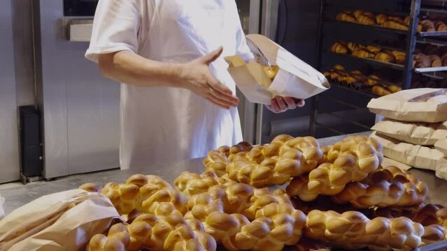 The baker took the cakes out of the oven and packed them in ecological paper packages. image from a small bakery with whole wheat products. Small successful bakery business