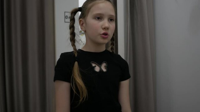 Dissatisfied irritated Caucasian girl vlogger model influencer frown looking choosing clothes. Stylish popular female blogger girl standing in fitting room in clothing store and putting uncomfortable 