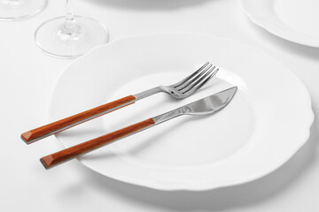 Stylish table setting with white dishware on white tablecloth