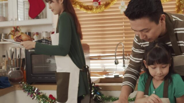 Happy Asian family spending times to prepare Chritsmas and Happy news year Celebrete. kids parent and grandparent doing ginger breads and bakery enjoy and dancing in kichen at home