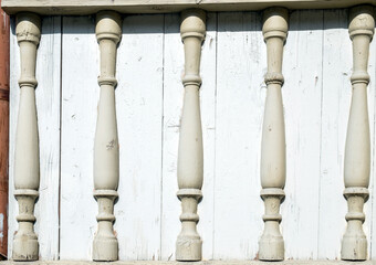 Old fashioned white wooden balusters in decoration of veranda railing. Old manor