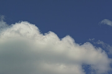 Obraz premium white cloud against a blue sky, illuminated by the sun from one side