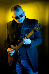 Portrait of a man with an electric guitar in his hands, made in a photo studio using color filters.