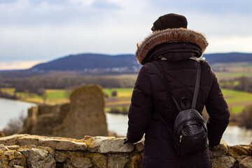 Woman tourist in black coat with black backpack at the top of Devin castle (Slovak: Devinsky hrad)....