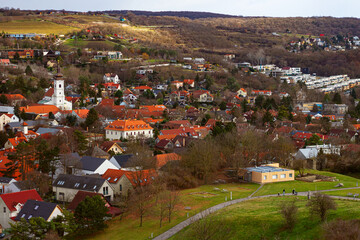 Fototapeta premium Devín district with cozy buildings with red tiles and Parish Church of the Holy Cross towering over the city. It is an important archaeological site situated near the ruins of Devín Castle