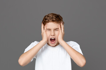 This image depicts a teenager in distress, holding his head and screaming, with an isolated grey...
