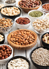Mixed raw nuts and seeds in bowls on kitchen table.Peanut,hazelnut,walnut,almonds,pistachio,sunflower,pumpkin,chia and cashew.Macro