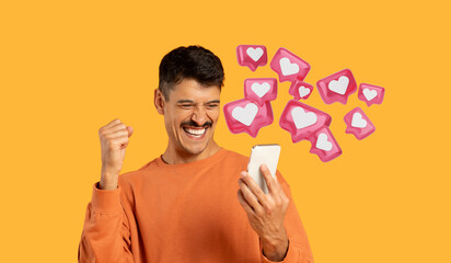 Isolated on orange, a millennial guy with moustache laughs and celebrates with his phone, got a love message from his girlfriend