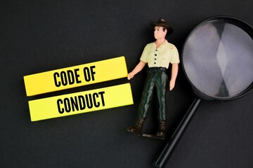 magnifying glass, miniature people and colored paper with the word code of conduct. the concept of...