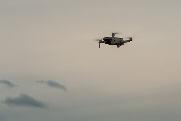 View on quadcopter drone flying in the evening sky. Remote controled drone with photo video camera..
