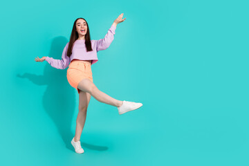 Full length photo of lovely young lady funny dancing dressed stylish violet garment isolated on aquamarine color background