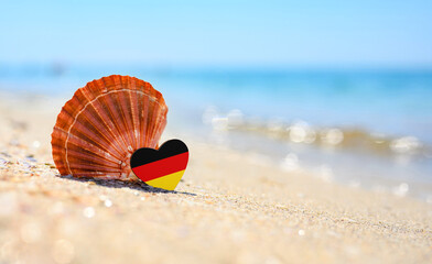 Obraz premium Flag of Germany in the shape of a heart and a large shell. A wonderful seaside resort.