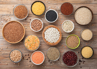 Bulgur,beans,quinoa,pea,couscous and hemp with chickpea and buckwheat seeds in various bowl plates on wooden kitchen background.Macro.