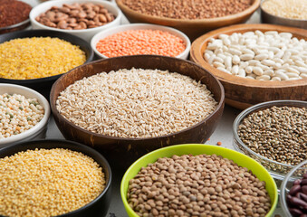 Bowls with various healthy cereals. Bulgur,beans,quinoa,pea,couscous and hemp with chickpea and buckwheat seed on light kitchen background.Macro.