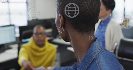 Image of globe icons moving over diverse business people in office