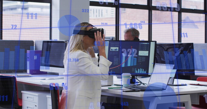 Image of statistical data processing against caucasian woman wearing vr headset at office