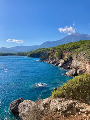 View of the cliffs and seishore with mountains and blue sky on the background in Phaselis (Kemer, Turkey)