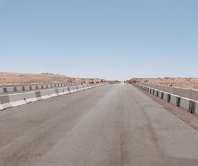 A road with a few cars on it. The road is empty and there are no people. The sky is clear and the sun is shining