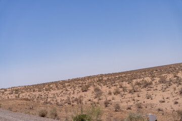 A vast, empty desert with a clear blue sky. The sky is so clear that it almost looks like a painting