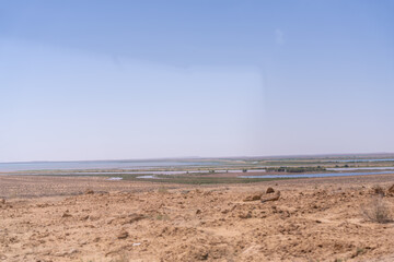 A desert landscape with a blue sky in the background. The sky is clear and the sun is shining brightly