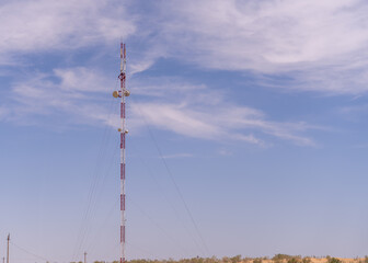 Obraz premium A tall tower with a red top is standing in a field. The sky is clear and blue, with a few clouds scattered throughout