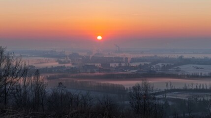 Fototapeta premium Sunrise over a factory town with visible air pollution layers from a high vantage point