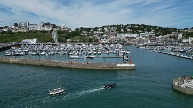 Torquay, Torbay, South Devon, England: DRONE VIEWS: A ketch is towed into Torquay marina by a motorboat. Torquay is a popular English holiday destination and a magnet for sailing enthusiasts.