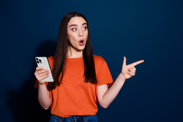 Photo of charming excited woman wear orange trendy clothes recommend offer empty space isolated on dark blue color background