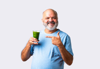 Elderly senior old Indian asian man eats green juice or drinking vegetable juice in a glass