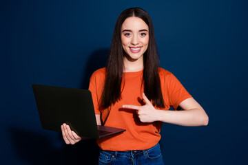 Photo of charming lovely woman wear orange stylish clothes recommend device isolated on dark blue color background