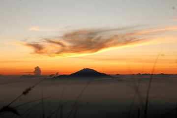 
A majestic sunrise over the mountains, a fine expanse of mist, an orange morning sky