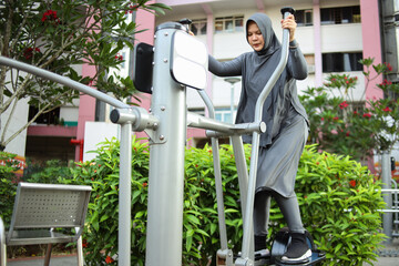Young Asian Woman Wear Hijab Making Exercises On Public Equipment In City Park.