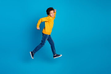Fototapeta premium Full size photo of small charming boy running fast black friday wear trendy yellow outfit isolated on blue color background