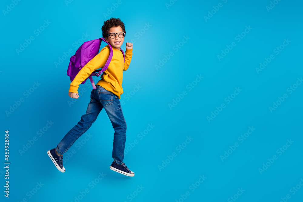 Poster Full size photo of small charming boy carry backpack schoolkid running wear trendy yellow outfit isolated on blue color background