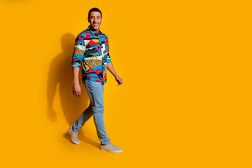 Full body photo of attractive young man walking dressed stylish colorful clothes isolated on yellow color background