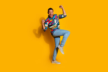 Full length photo of nice young male winning raise fists dressed stylish colorful garment isolated on yellow color background