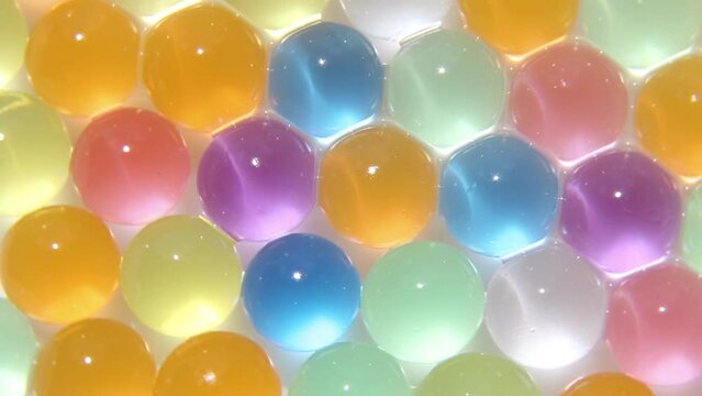 Colorful,shiny, little balls are spinning. a background of hydrogel, luminous, colored balls in motion. Macro photography. Asmr.