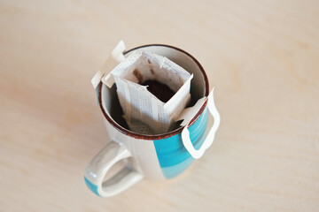 Drip bag fresh coffee. Pouring hot water into blue cup with drip coffee bag. Instant freshly brewed cup of ground coffee. Coffee Trend. Quick way to brew using paper filter. The process of brewing