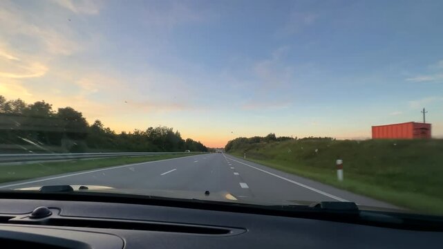 Car dashboard, windscreen view driving on motorway A13 near Klaipeda city in Western Lithuania before the dusk, selective focus on foreground.