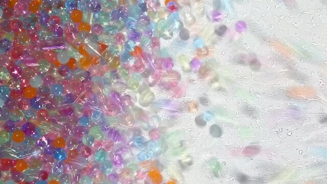 Multicolored little balloons are flying, jumping on a white background. a background of hydrogel colored balls in motion. Asmr.