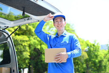 外で荷物を運ぶ配送ドライバーの笑顔の男性