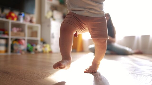 Family. The first steps to bringing your baby home. Child mother toddler family concept. Baby learns to walk indoors. A baby lifestyle running on a wooden floor with a woman.