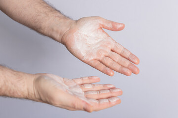 Fototapeta premium Male hands with palms full of cosmetic product isolated on grey background. Copy space. Concept of cosmetics, male care and hair care