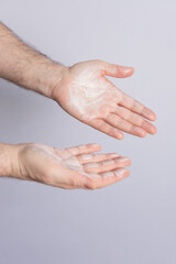 Fototapeta premium Male hands with palms up filled with cosmetic product isolated on grey background. Copy space. Concept of cosmetics, male care and hair care