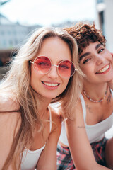 Two young beautiful smiling hipster female in trendy summer white t-shirt and shorts clothes. Sexy carefree women posing in the street. Positive models having fun, hugging and going crazy, sunglasses