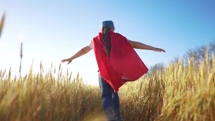 Superhero running through the wheat with his child. Hero super costume concept. girl runs across a field of wheat with a superhero. Girl runs through a fun field of wheat and runs into a superhero. © maxximmm