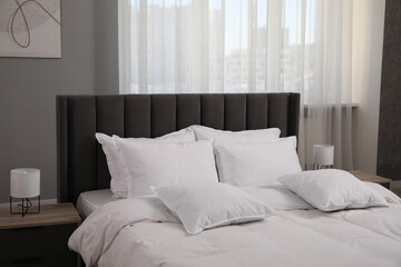 Many soft white pillows and duvet on bed indoors
